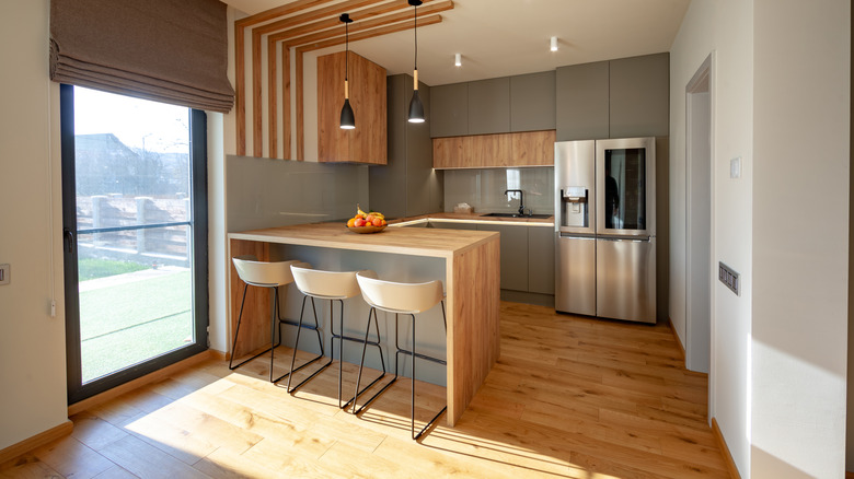 A modern kitchen with a peninsula with wood accents.