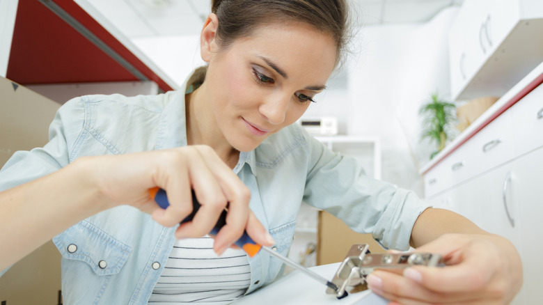 Woman unscrewing cabinet doorhinge