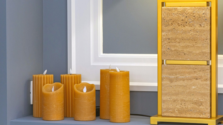 Six light brown flameless candles sitting next to a mirror
