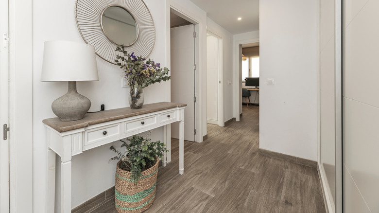 Foyer with a lamp on the table next to a mirror