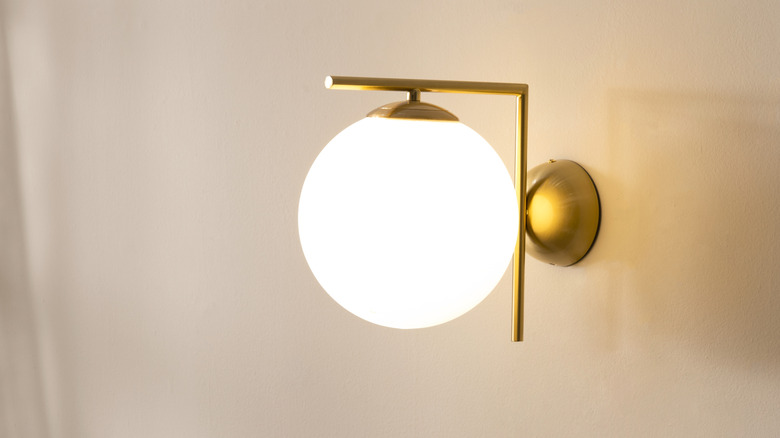 Gold wall sconce with a frosted glass globe-style shade