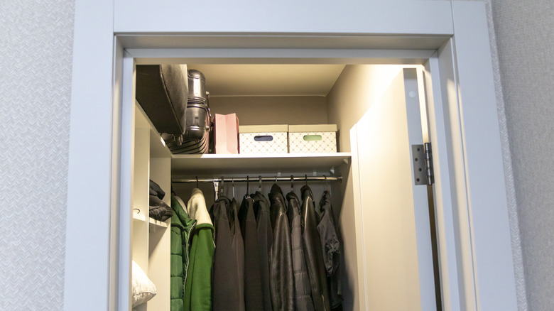 Entryway closet with coats and stored items and an overhead light shining
