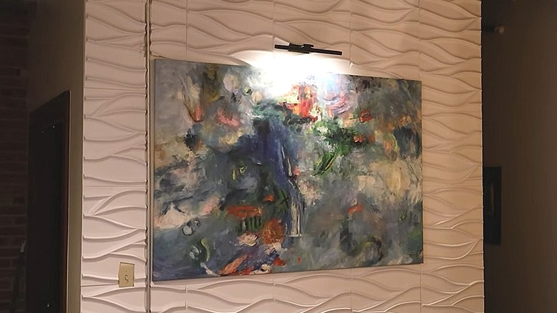 Battery-powered picture light installed above an abstract painting on a textured wall