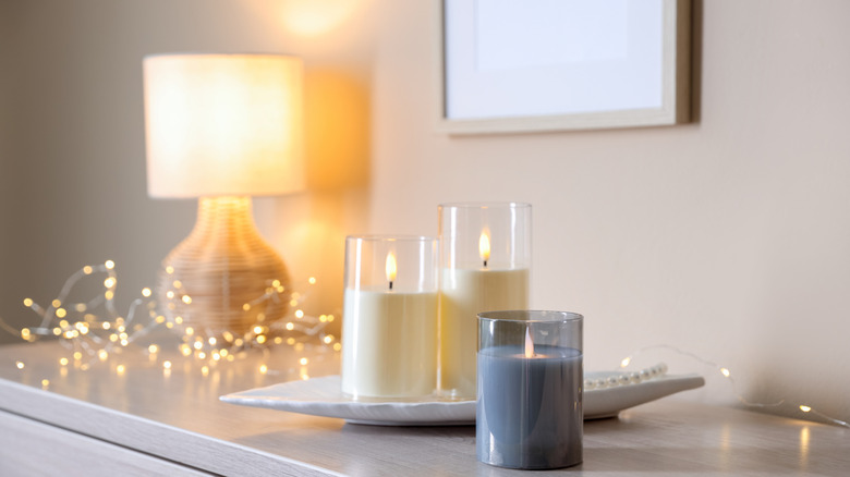Bunches of fair lights sitting on a table next to a lamp and candles