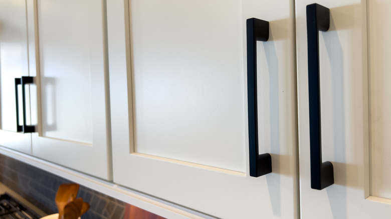 Matte black cabinet pulls on white upper kitchen cabinets