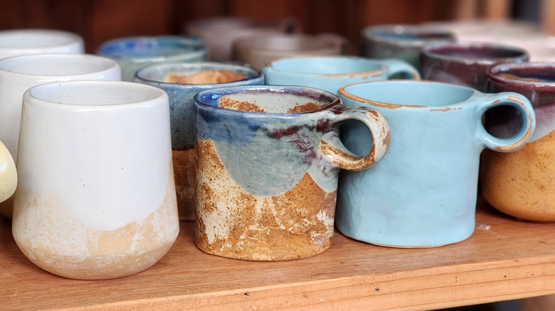 Rows of handcrafted mugs on a shelf