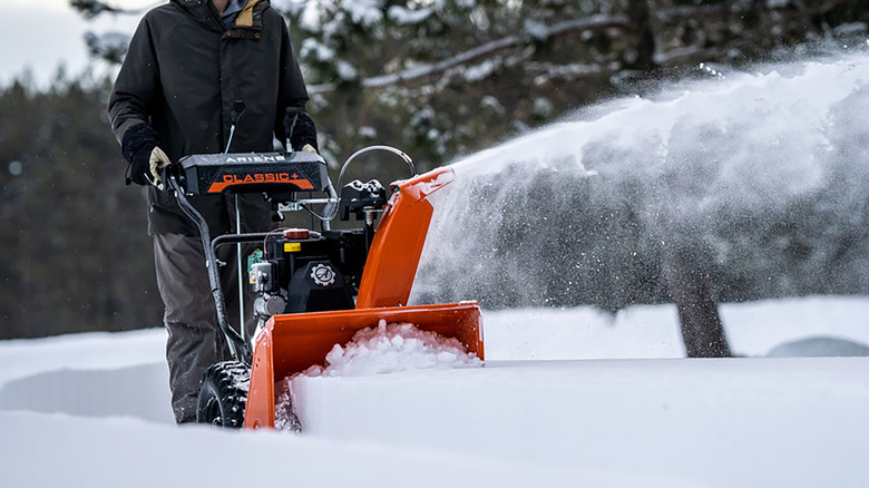 Person using the Ariens 920025 Classic 24 in. Gas Snow Blower