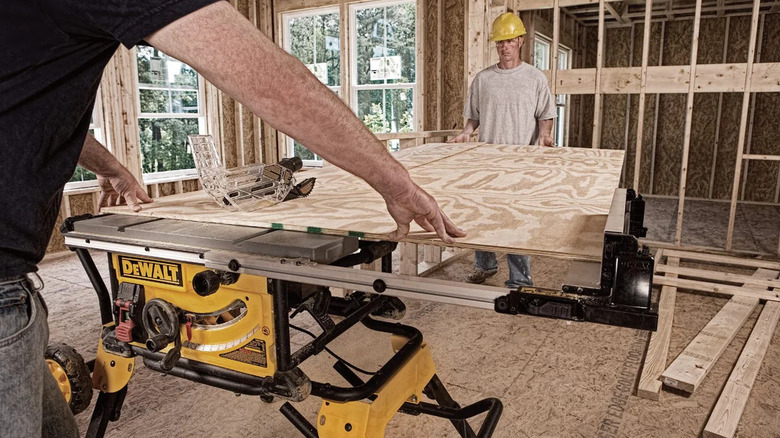 Two men cutting a board using the DeWalt DWE7491RS Job Site Table Saw