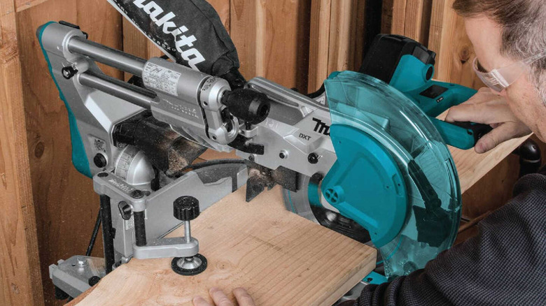 Man cutting a board using the Makita LS1219L 12-inch Compound Miter Saw