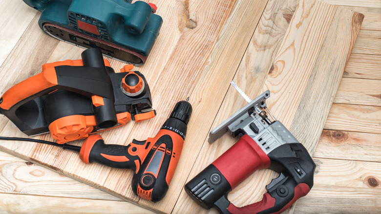 Several power tools resting on a piece of wood
