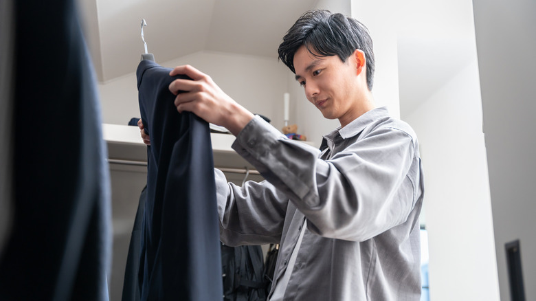A person examining a jacket in the closet