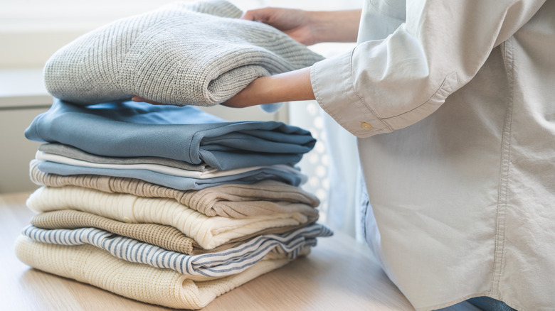 Woman stacking sweaters on table
