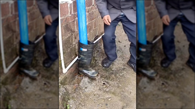 Man putting rain boot over downspout