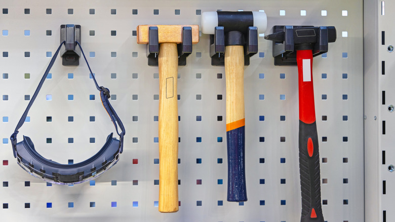 A pair of safety goggles hanging from a pegboard alongside tools