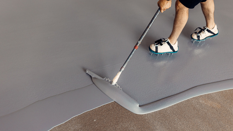 A worker applying a fresh coat of floor paint
