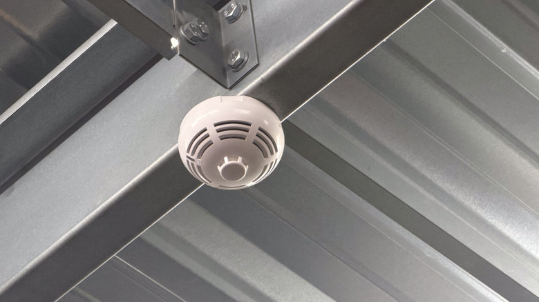 A smoke detector on the metal ceiling of a garage
