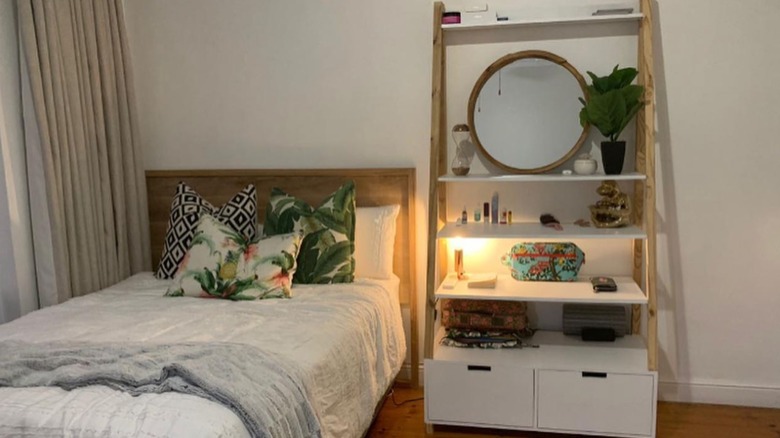 A tall shelf next to a bed