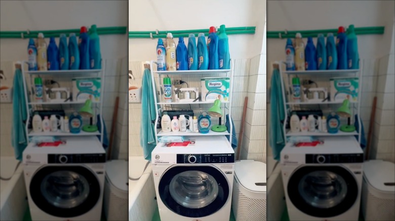 A person places laundry detergent on a white shelf over a washing machine