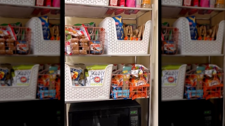 A person organizes snacks above a mini fridge