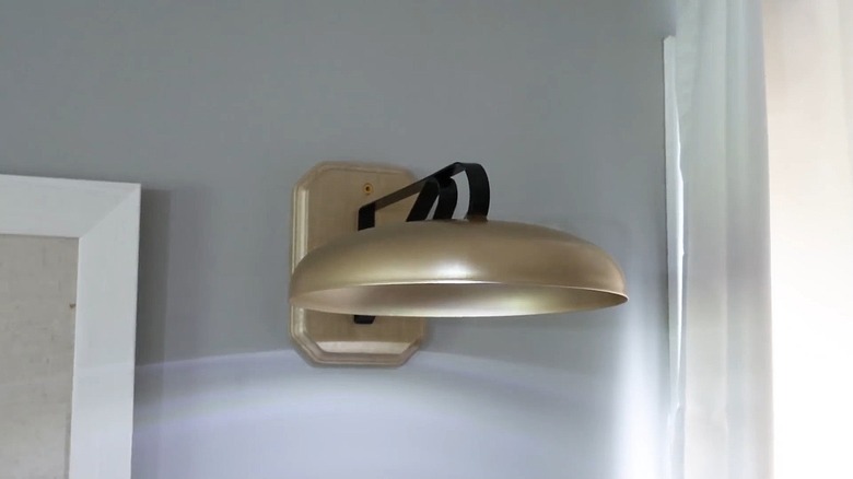 Gold farmhouse sconce mounted on wood piece on the wall