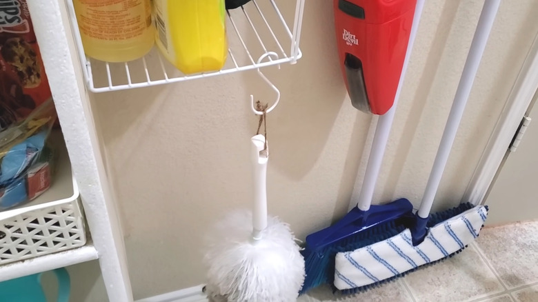 White fluffy duster with a twine strap hanging from a plant hook in a utility closet