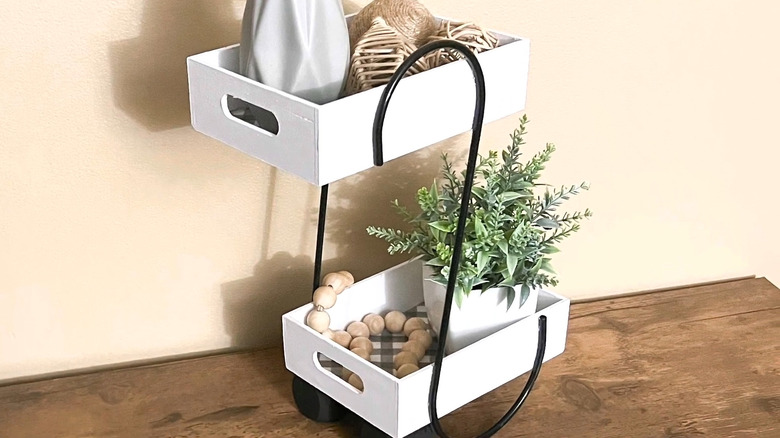 White wooden tray shelf holding decorative items and made using large black garden hooks