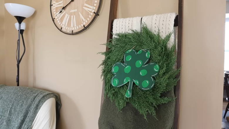 Green wreath with a decorative shamrock hanging on a garden hook