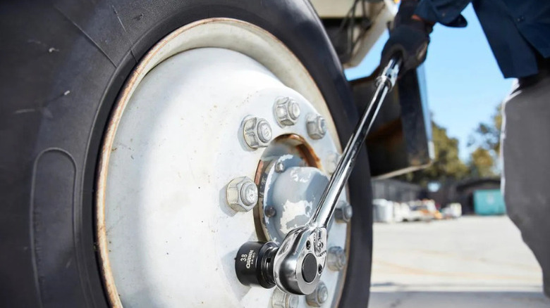 A person using Quinn's extendable ratchet to remove bolds from a wheel