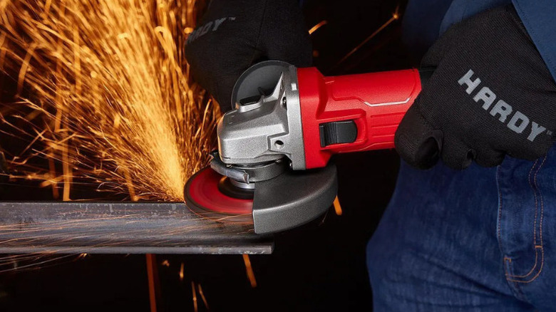 Sparks flying from metal as a worker grinds it with a red angle grinder