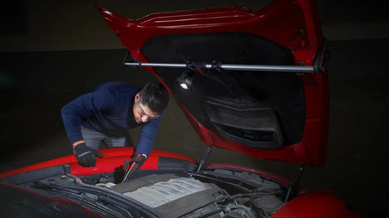 A man working on a car motor, illuminated with Icon's magnetic underhood floodlight
