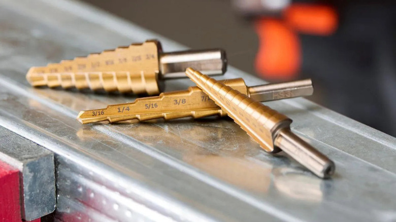 Stepped drill bits, made by Warrior, resting on a metal surface