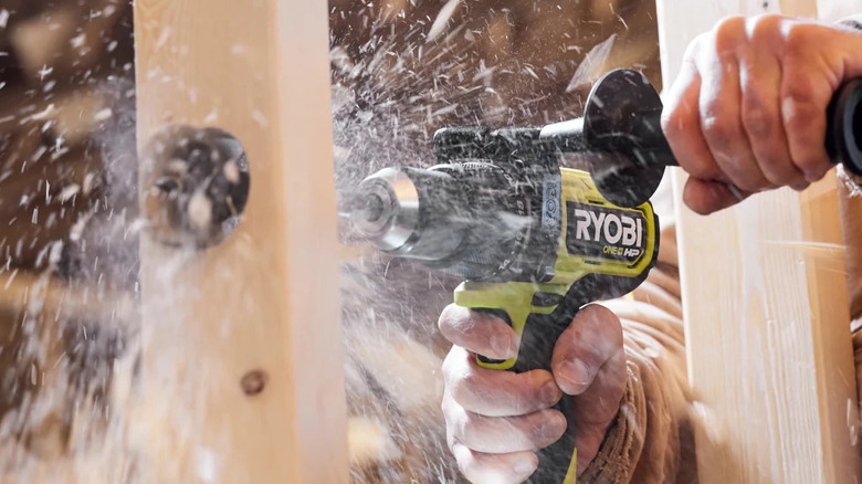 A person drilling wood with Ryobi's 18V One+ Brushless ½-inch Hammer Drill