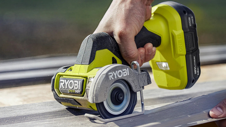 Close-up of a person cutting siding with Ryobi's 18V One+ Brushless Cordless Compact Cut-Off Tool