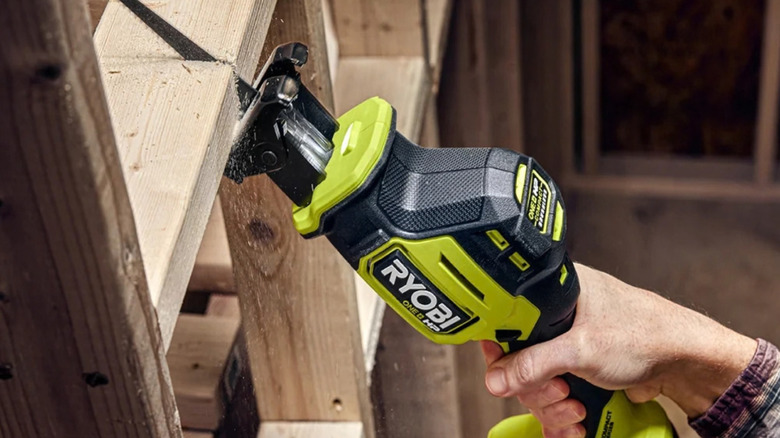 A person cutting wood frames with a Ryobi reciprocating saw