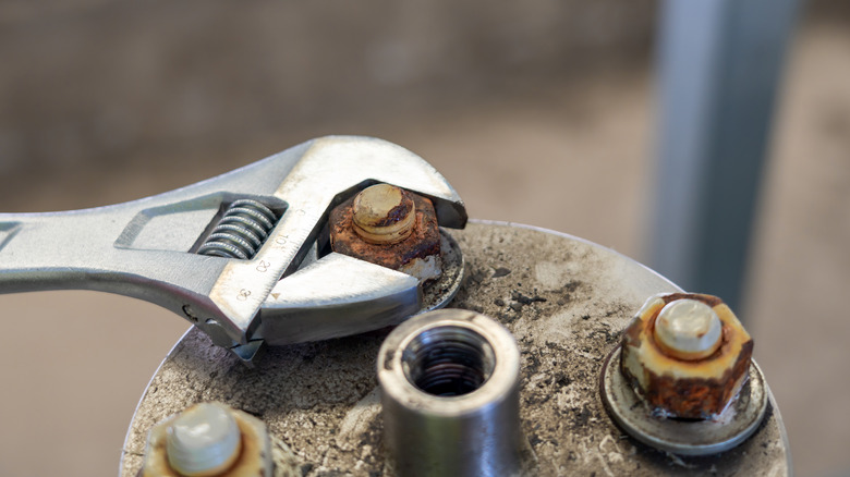 Close-up of a wrench loosening a rusty bolt