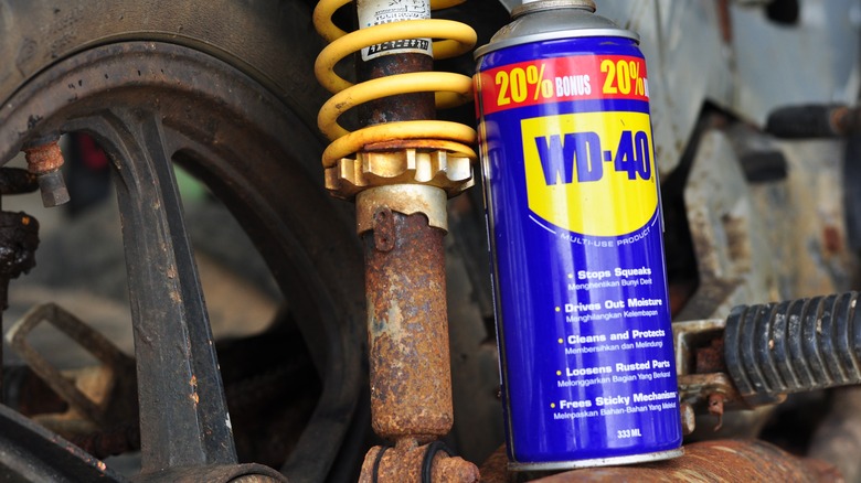 A can of WD-40 next to a rusted metal car part