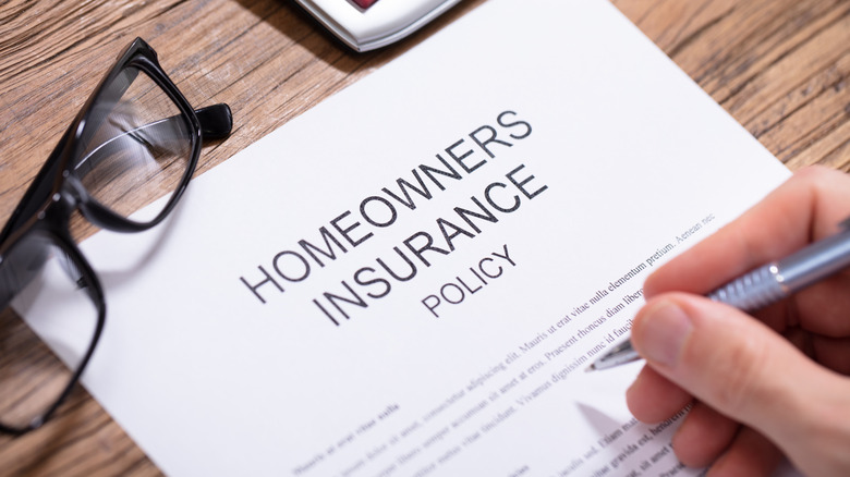 A person signing a homeowners insurance document