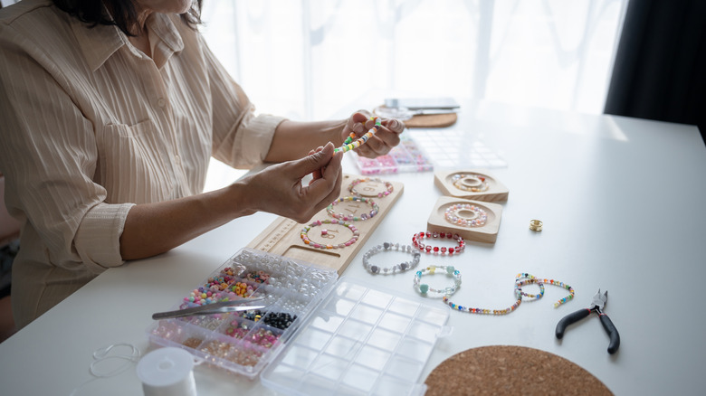 A person sitting at a table making jewelry