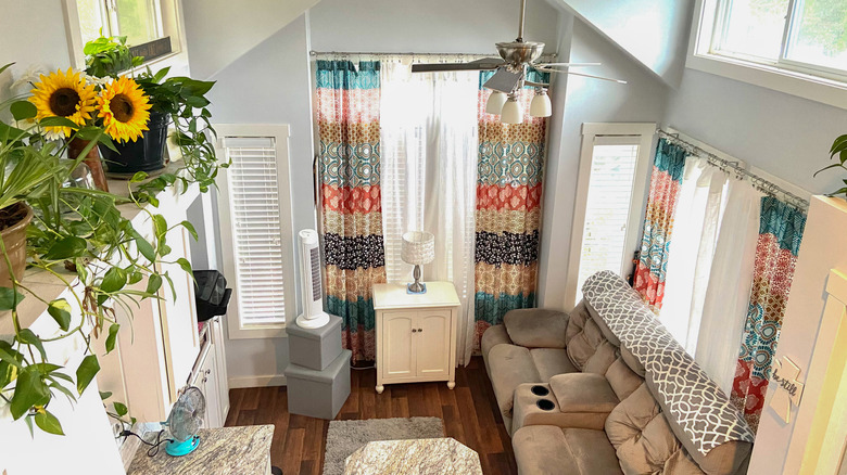 The interior of a tiny home decorated with sunflowers, colorful curtains, and lots of natural light