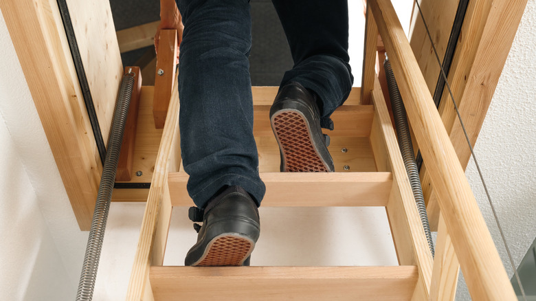 A close-up of a person's feet and legs as they climb a loft ladder