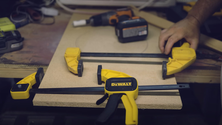 Pair of DeWalt trigger clamps laid out in garage with drill