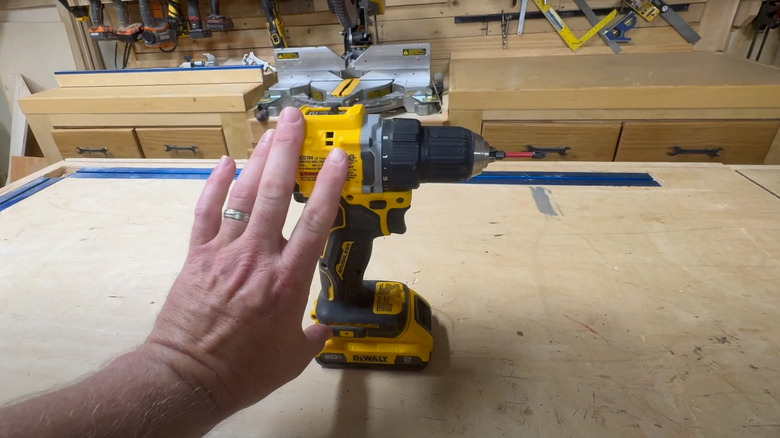 Hand resting on DeWalt drill driver on wood worktop