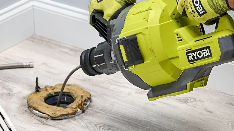 A person unblocking a drain with Ryobi's 18V One+ Cordless Drain Auger with 35-ft cable