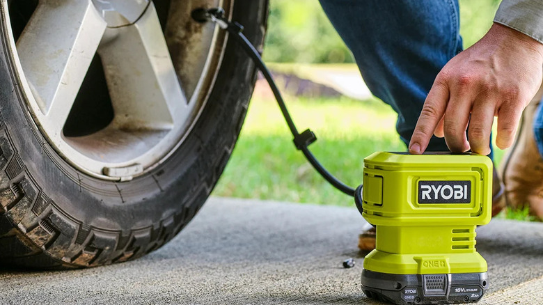 A person inflating a car tire with Ryobi's 18V One+ Cordless High Pressure Inflator