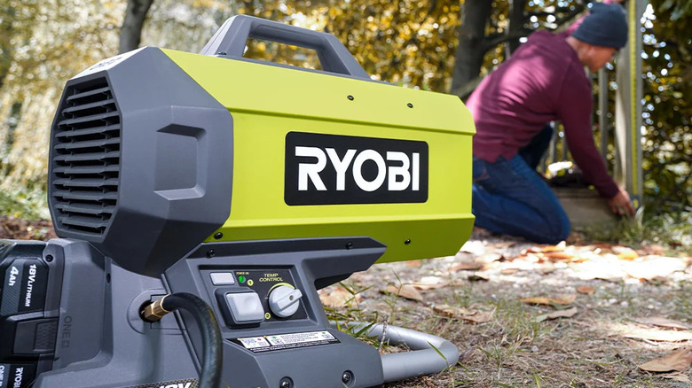 A person working outdoors with Ryobi's 18V One+ Cordless Hybrid Forced Air Propane Heater