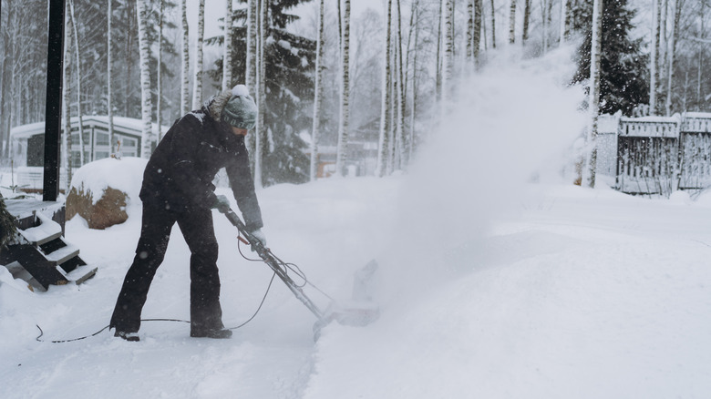 Person using a snowblower in a driveway