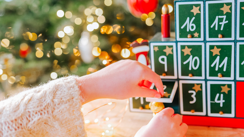 person taking gift out of wood advent calendar