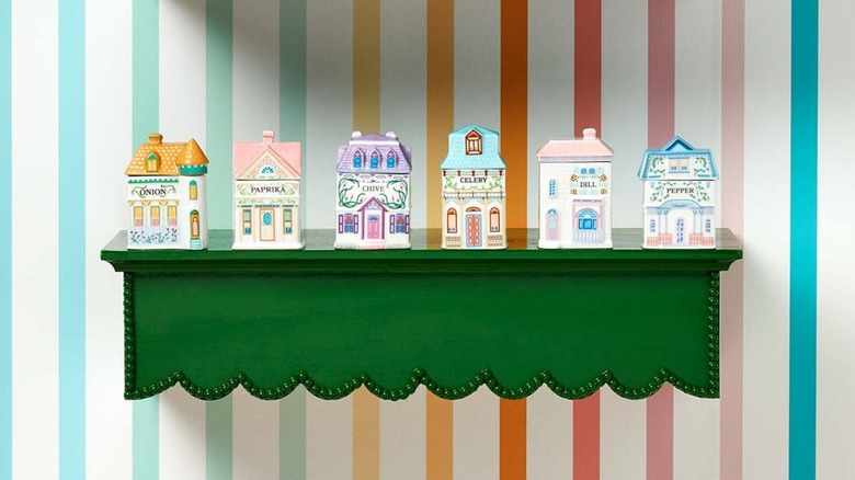 Lenox Spice Village spice holders in pastel colored ceramic houses on green shelf against striped background