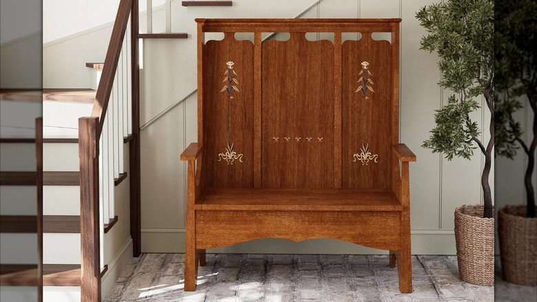 Stickley decorative wooden Fireside Bench with subtle details in a front hallway between staircase and small potted tre