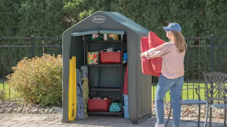 A woman loading red pillows into the Scotts storage shed.